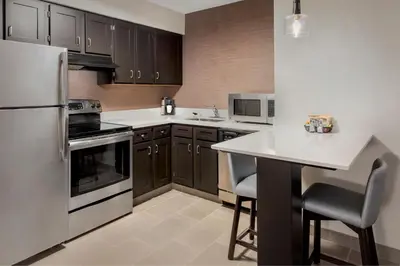 a kitchen with a refrigerator and a table with chairs at Residence Inn Hartford Manchester in Manchester