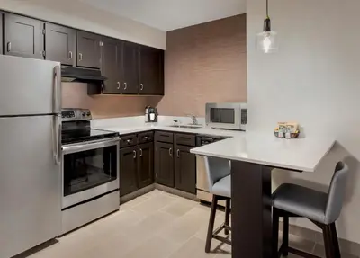 a kitchen with black cabinets and a white refrigerator at Residence Inn Hartford Manchester in Manchester