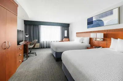 a hotel room with two beds and a television at Courtyard Hartford Farmington in Farmington
