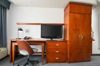 a room with a desk with a tv and a chair at Courtyard Hartford Farmington in Farmington