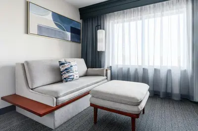 a living room with a chair and a ottoman at Courtyard Hartford Farmington in Farmington