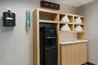 a black refrigerator in a shelf with a clock on the wall at Courtyard Hartford Farmington in Farmington