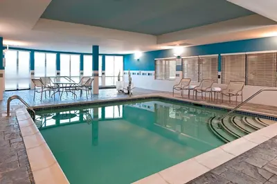 a swimming pool with tables and chairs in a building at Courtyard Hartford Farmington in Farmington