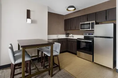 a kitchen with a table and a refrigerator at Residence Inn Hartford Rocky Hill in Rocky Hill