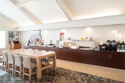 a dining room with a table and a kitchen at Residence Inn Southington in Southington