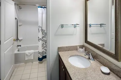 a bathroom with a sink and a mirror and a tub at Residence Inn Milford in Milford