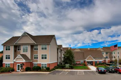 a large apartment building with cars parked in a parking lot at Residence Inn Milford in Milford