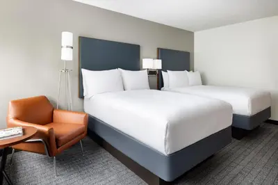 a hotel room with two beds and a chair at Courtyard Montvale in Montvale