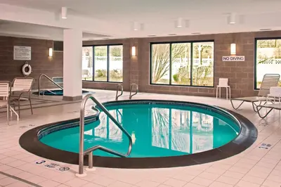 a pool in a hotel lobby with tables and chairs at Courtyard Newburgh Stewart Airport in Newburgh
