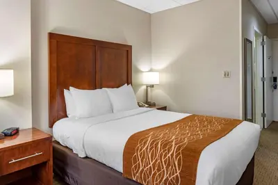 a hotel room with a large bed with a wooden headboard at Comfort Inn Syosset-Long Island in Syosset