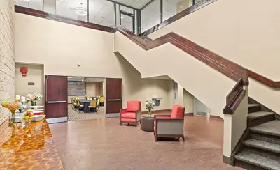 an office lobby with a staircase with red chairs at Comfort Inn Syosset-Long Island in Syosset