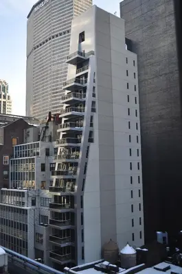a tall white building in front of some buildings at The Gotham Hotel in New York