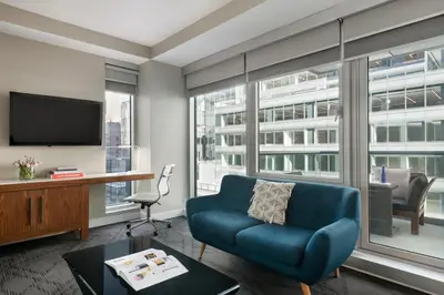 a living room with a blue couch and a tv at The Gotham Hotel in New York