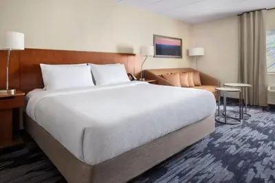 a hotel room with a large bed and a chair at Fairfield by Marriott Inn & Suites Wallingford New Haven in Wallingford