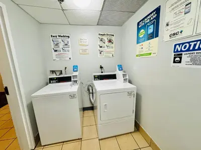 a laundry room with two machines and signs on the wall at Motel 6-Milford, CT in Milford