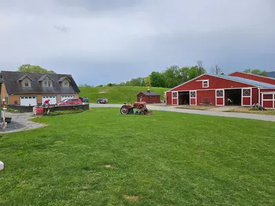 a tractor parked in a field next to a barn at Clover Hill Farm & Country Inn in Williamstown