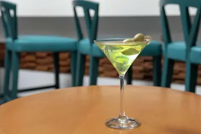 a martini glass on a table with olives in it at Hilton Garden Inn Westchester Dobbs Ferry in Dobbs Ferry