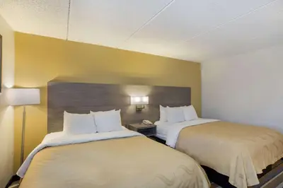 two beds in a hotel room with yellow walls at Quality Inn Albany Colonie in Albany