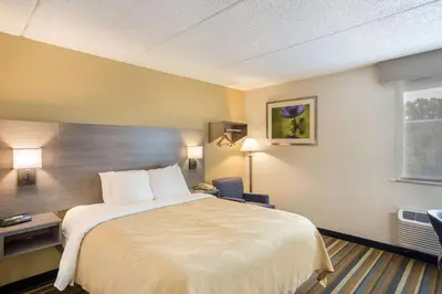 a hotel room with a bed and a desk and a window at Quality Inn Albany Colonie in Albany