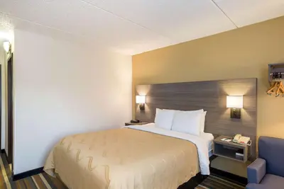 a hotel room with a bed and a blue chair at Quality Inn Albany Colonie in Albany