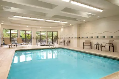 a pool in a hotel with chairs and tables at Courtyard by Marriott Middletown Goshen in Middletown