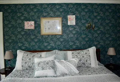 a bedroom with green wallpaper and a bed with pillows at Harbour House Inn B&B in Cheshire
