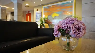 a vase filled with purple flowers sitting on a table at Best Western Queens Court in Queens