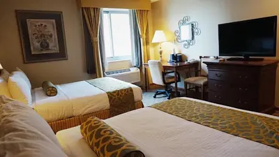 a hotel room with two beds and a desk at Best Western Queens Court in Queens