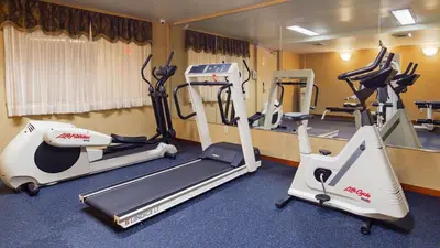 a gym with treadmills and elliptical machines at Best Western Queens Court in Queens