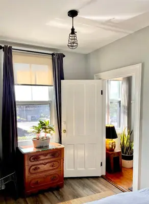 a bedroom with a white door and a dresser with plants at Wm. Farmer and Sons in Hudson