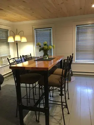 a dining room table with chairs and a vase of flowers on it at Wind in the Willows Overnight in Jefferson
