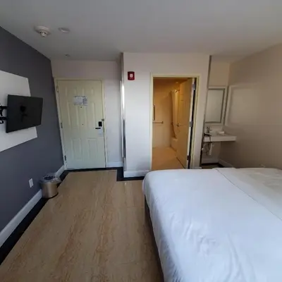 a bedroom with a white bed and a hallway at Mayfair Inn and Suites in Queens