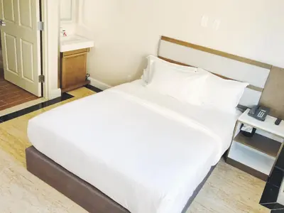 a bedroom with a large bed with white sheets at Mayfair Inn and Suites in Queens