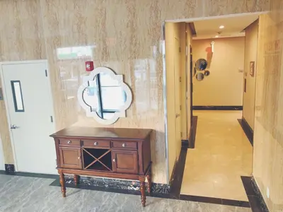 a hallway with a wooden dresser and a clock on the wall at Mayfair Inn and Suites in Queens