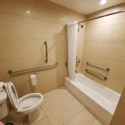a bathroom with a toilet and a tub and a sink at Mayfair Inn and Suites in Queens