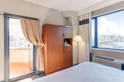 a bedroom with a cabinet and a large window at Vista LIC Hotel, Premier Collection by Best Western in Queens
