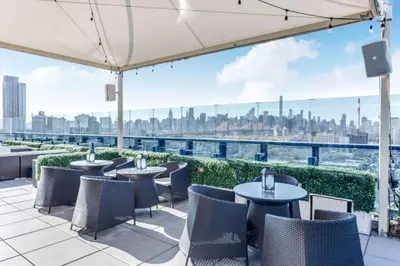 a patio with tables and chairs and a view of the city at Vista LIC Hotel, Premier Collection by Best Western in Queens