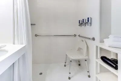 a white bathroom with a chair and a shower at Vista LIC Hotel, Premier Collection by Best Western in Queens