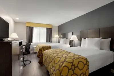 a hotel room with two beds and a desk at Baymont by Wyndham Branford/New Haven in Branford