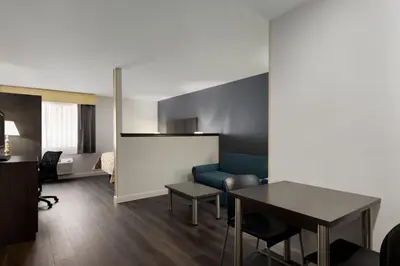 a living room with a blue couch and a table at Baymont by Wyndham Branford/New Haven in Branford
