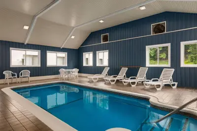 a swimming pool with lounge chairs and a table and a tablektop at Baymont by Wyndham Branford/New Haven in Branford