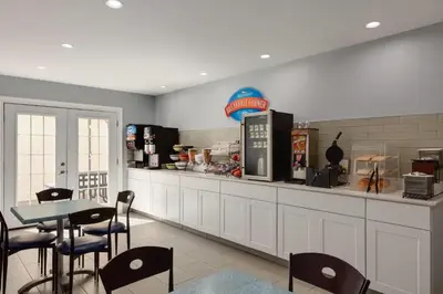 a restaurant with a counter and a table with chairs at Baymont by Wyndham Branford/New Haven in Branford