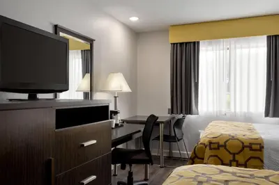 a hotel room with a bed and a desk with a television at Baymont by Wyndham Branford/New Haven in Branford