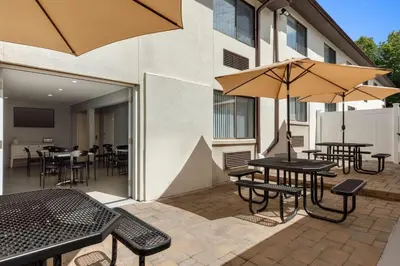 a patio with tables and chairs and umbrellas at Baymont by Wyndham Branford/New Haven in Branford