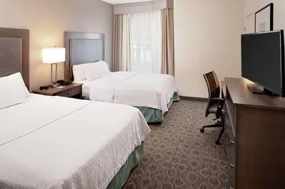 a hotel room with two beds and a flat screen tv at Homewood Suites by Hilton Hartford-Farmington in Farmington