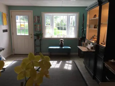 a room with a dog sitting on a bench in front of a window at Harwood Hill Motel in Bennington