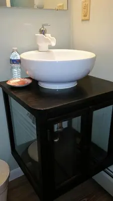 a sink on top of a black table with a bottle of water at Harwood Hill Motel in Bennington
