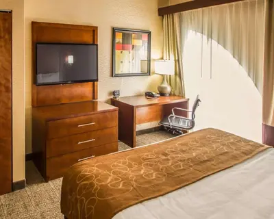a hotel room with a bed and a desk and a television at Quality Suites NYC Gateway in North Bergen