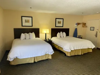 a hotel room with two beds and a room with two lamps at Whitney Inn & Suites in Hamden