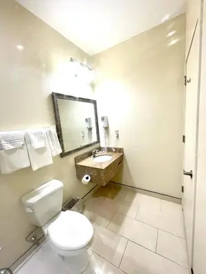a bathroom with a toilet and a sink and a mirror at Whitney Inn & Suites in Hamden